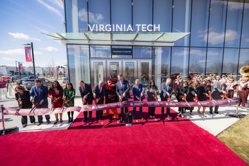 Ribbon cutting People cut a ribbon marking the entrance to a new building.